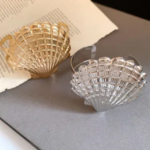 Detalle de brazaletes abiertos con forma de concha en color oro y plata estilo vintage