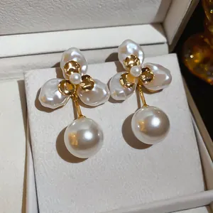Close-up of elegant gold plated flower earrings with pearl drops in a luxury gift box.