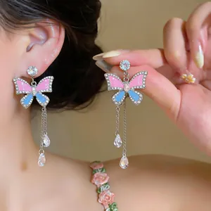 Close-up of pink and blue enamel butterfly drop earrings with rhinestone details