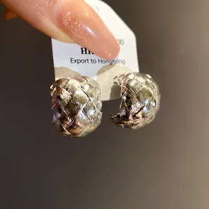 Détail de boucles d'oreilles clous vintage argentées en forme de C avec texture tissée