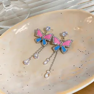 Detailed close-up of luxury enamel butterfly earrings with sparkling crystal teardrops