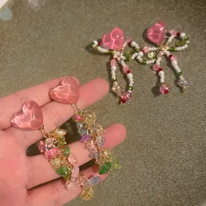 Close-up detail of heart earrings with colorful gravel tassels in island style