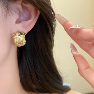 Gros plan détaillé de boucles d'oreilles en forme de C dorées et texturées de style vintage