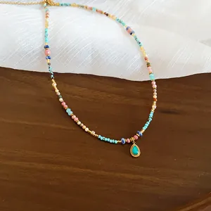Detail einer bunten Perlenkette mit einem goldgefassten Tropfenanhänger aus Türkis.