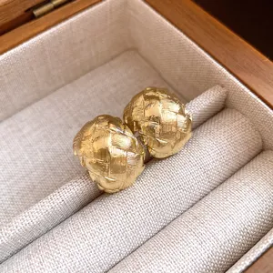 Gros plan de boucles d'oreilles rétro dorées avec motif tressé dans une boîte à bijoux.