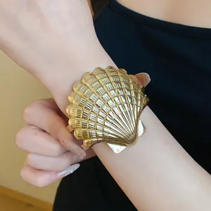 Detalle de un brazalete abierto de metal dorado con forma de concha de estilo vintage