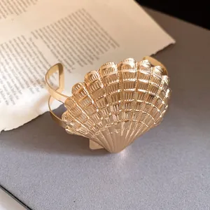 Vista detallada del brazalete abierto dorado con forma de concha de estilo retro