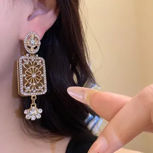 Close-up detail of vintage gold-toned square drop earrings with sparkling rhinestones