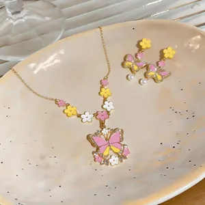 Detailed view of the colorful enamel butterfly necklace and matching pearl earrings on a tray.