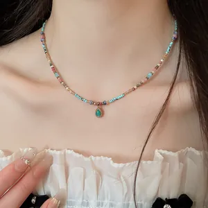 Nahaufnahme einer bunten Perlenkette mit Tropfenanhänger, von einem Model getragen.