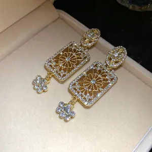Close-up of vintage gold-tone rectangular dangle earrings with intricate floral pavé stones