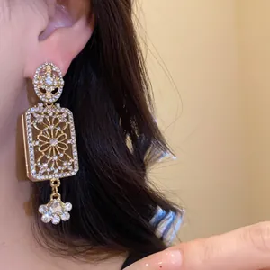 Close-up of vintage gold-plated square earrings with intricate rhinestone patterns