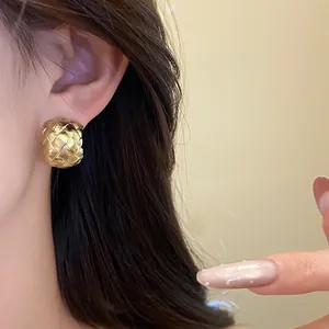 Gros plan détaillé de boucles d'oreilles dorées en forme de C avec texture tressée