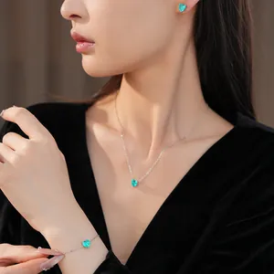 Elegant jewelry set with green zircon heart necklace, earrings, and bracelet on model.