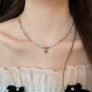 Detailansicht einer bunten Perlenkette mit einem grünen Tropfenanhänger an einem Modell