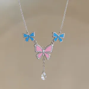 Close-up of pink butterfly and blue bow-tie pendant with crystal teardrop detail