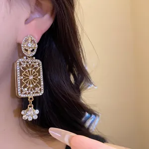 Close-up of vintage rhinestone square dangle earrings in palace style worn on model