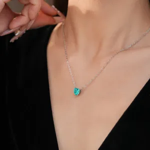 Elegant silver chain with a green heart-shaped gemstone pendant worn by a model
