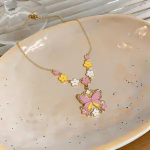 Detail of a gold necklace featuring a colorful oil-dripping butterfly and flower pendant.