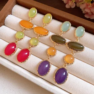 Detailed view of vintage multi-colored oval resin dangle earrings in a jewelry box