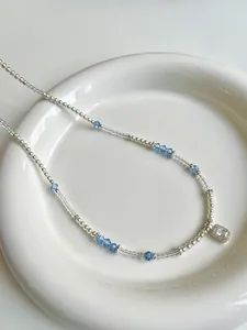 Detail shot of a beaded pearl necklace with blue crystals and a zircon pendant