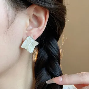 Minimalist wrinkled diamond stud earrings featuring elegant mother of pearl inlay design