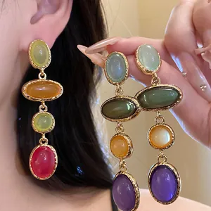 Close-up of vintage multi-colored oval resin drop earrings with golden textured metal