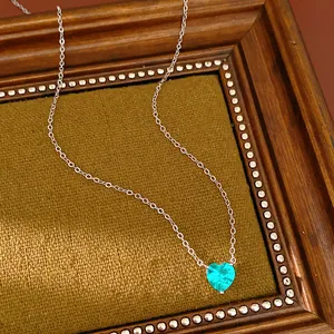 Detailed close-up view of a heart-shaped green zircon pendant on a silver necklace chain