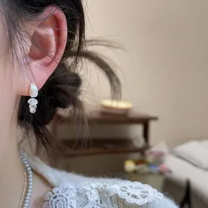 Detailed close-up of a silver zircon teardrop tassel earring worn on a female ear