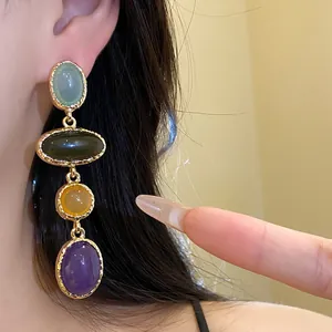 Detailed shot of vintage-style colorful resin oval drop earrings on a model's ear.