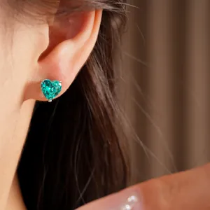 Detailed close-up view of a heart-shaped green zircon stud earring worn on a model's ear