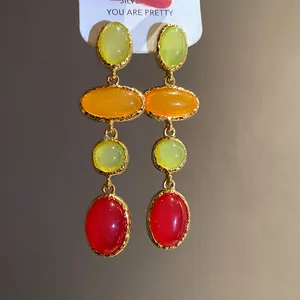 Close-up of vintage resin drop earrings with vibrant green, orange and red stones