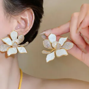 Close-up of elegant gold-plated flower stud earrings with pearls and cubic zirconia