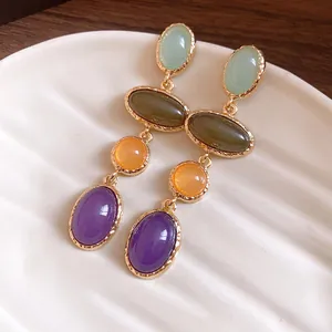 Detailed close-up of vintage-style colorful resin oval drop earrings in gold setting