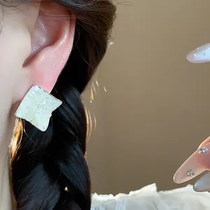 Close-up of mother-of-pearl diamond stud earring worn on an ear