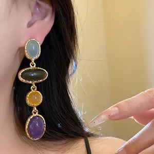 Close-up view of vintage-style oval resin dangling earrings worn by a model for detail