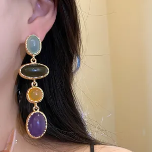 Detail shot of vintage multi-color resin oval pendant dangling earrings worn on ear.