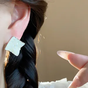 Detail view of wrinkled rhombus stud earrings with elegant mother of pearl inlay.