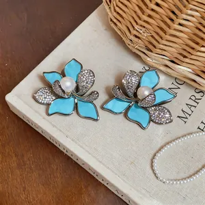 Macro detail of elegant blue enamel flower stud earrings with pearl and clear zircon