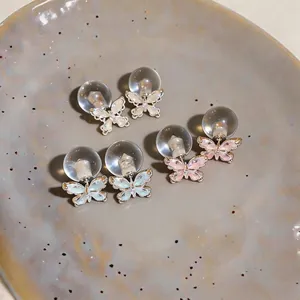 Detailansicht eleganter Schmetterling-Ohrstecker mit Zirkonsteinen auf Keramikteller