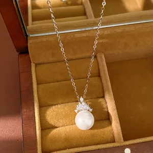 Gros plan d'un collier de perles plaqué or 18 carats avec couronne en zircone en boîte