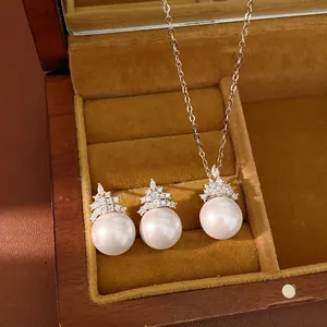 Vue rapprochée détaillée d'un ensemble collier et boucles d'oreilles en perles et zircon en boîte.