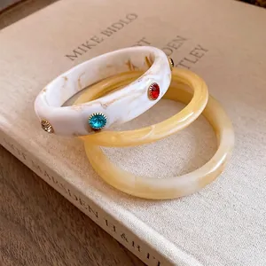 Vintage gemarmerde hars armbanden set met kleurrijke stenen op een retro boek achtergrond.