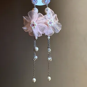 Vue détaillée de boucles d'oreilles pendantes en mousseline rose avec perles et cristaux brillants