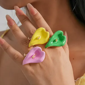 Primer plano de anillos esmaltados de colores con forma de cala en una mano, detalle