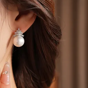 Gros plan de boucles d'oreilles élégantes en perles et sapin de Noël avec zircons
