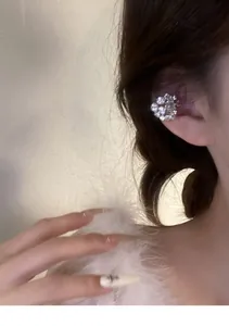 Detailed view of a sparkling silver micro-pave crystal ear cuff worn on a model's ear.
