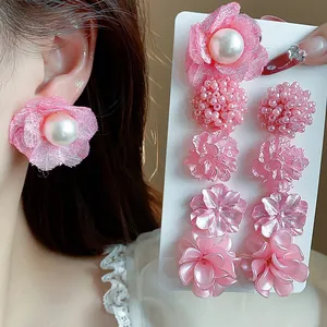 Vista detallada del juego de pendientes de flores rosas y perlas en la oreja del modelo