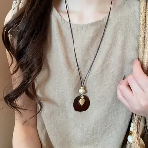 Close-up of bohemian retro circular necklace with a gold heart charm on a model