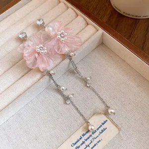 Détail de boucles d'oreilles pendantes en mousseline rose avec perles et cristaux